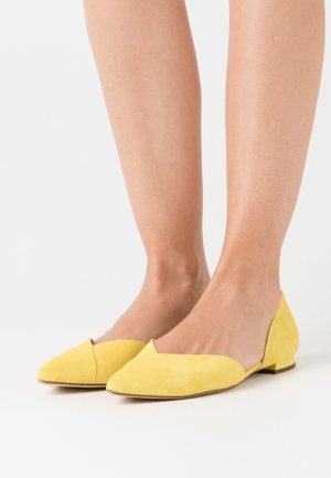 Ballerines en daim jaune avec un bout pointu et un petit talon, présentant un design en forme de V et une texture douce, idéales pour une tenue décontractée ou semi-formelle.