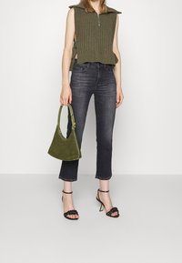 Haut sans manches côtelé kaki avec fermeture éclair, assorti à un jean noir court et des talons noirs à lanières. Complété par un sac à main en daim vert.