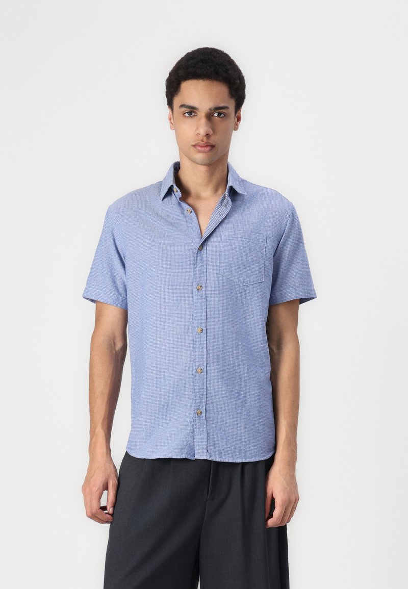 Chemise à manches courtes, bleu clair, à boutons, avec un subtil motif à carreaux, une poche poitrine unique et des boutons de teinte naturelle.