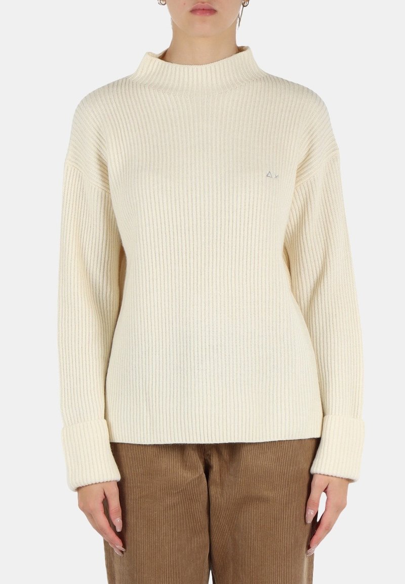 Maglione a coste di colore crema con colletto alto, vestibilità ampia e polsini larghi. Presenta un piccolo logo sul lato sinistro del petto.