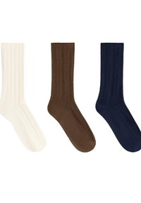 Trois chaussettes à côtes de couleur crème, marron et bleu marine, disposées horizontalement sur un fond blanc.
