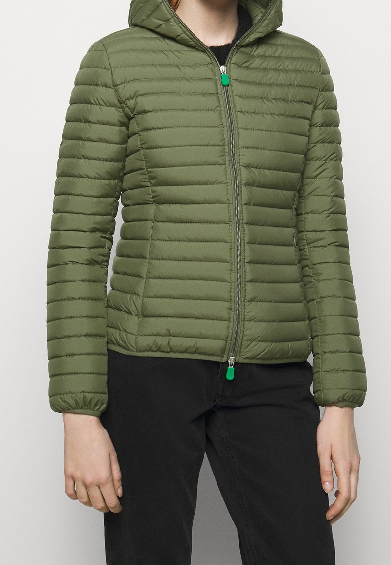 Veste en duvet verte avec fermeture éclair à l'avant, capuche et poignets côtelés. Présente une texture matelassée et lisse, avec un accent de tirage contrasté.