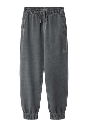 Grå joggingbukser med elastik i taljen, forlommer, snøre, manchetter ved anklerne og et lille logo patch på højre ben.