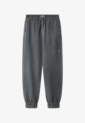 Grå joggingbukser med elastik i taljen, forlommer, snøre, manchetter ved anklerne og et lille logo patch på højre ben.