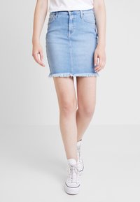 Light blue denim mini skirt with a fitted silhouette, frayed hem, five-pocket design, and belt loops, paired with white high-top sneakers.