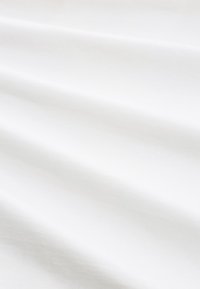 Fehér szövet sima textúrával és puha redőkkel, tiszta, egyenletes felülettel és minimális látható mintákkal vagy részletekkel.