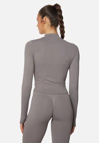 Long-sleeve, fitted top in soft gray material with a mock collar, smooth texture, and seamless design, paired with matching leggings.