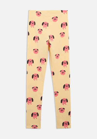 Žluté legíny se vzorem opakujících se růžových kreslených psích obličejů s černýma ušima, zobrazené natažené na světlém pozadí.