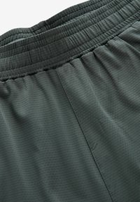 Mørkegrå sports shorts med en tekstureret overflade, elastisk talje og sy-detaljer, designet til komfort og bevægelsesfrihed.