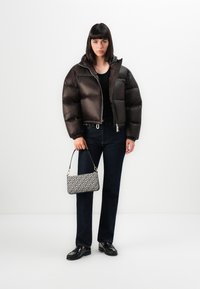 Giacca marrone imbottita con cappuccio, maglietta nera, jeans blu scuro, mocassini neri e borsa a motivo con tracolla nera.