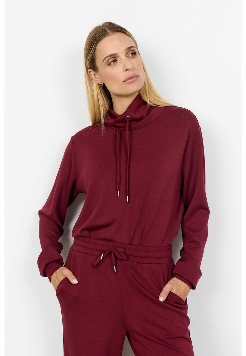 Burgundia värvi neist hülgava kaelusega pullover, millel on nööriga reguleeritav kaelus, pikad varrukad ja mugav lõige. Omab küljetaskuid ja sujuvat tekstuuri.