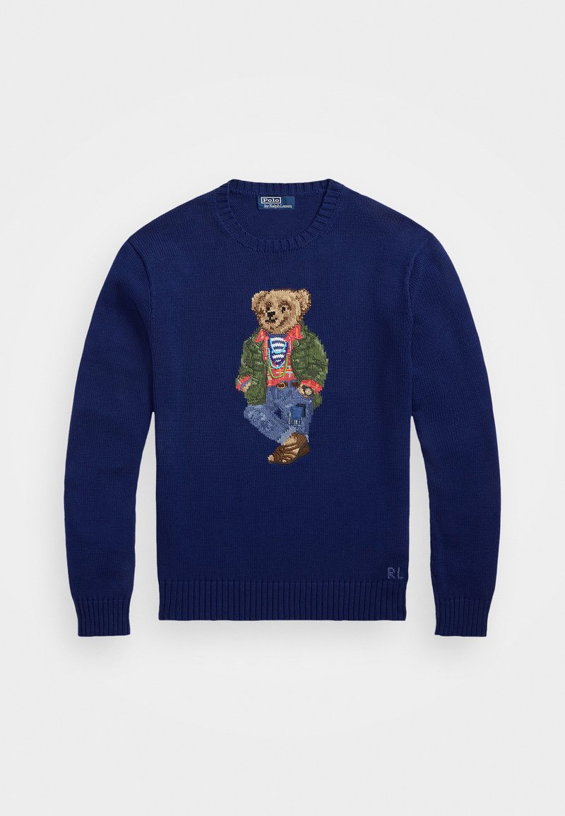 Jūrinės mėlynės megztinis su išsiuvinėtu lokiu žaliame švarkelyje ir džinsuose. Klasikinio apvalaus kaklo ir guma užbaigtomis rankovėmis bei apatine dalimi.