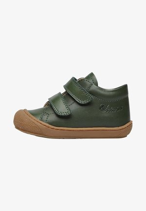 Chaussure en cuir vert avec deux bandes Velcro, bout arrondi et semelle en caoutchouc beige. Comprend des détails de couture et un capuchon de pointe texturé.