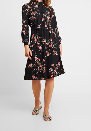 Black floral dress with long sleeves and gathered waist, featuring pink and green patterns, flowing fabric, and a flared skirt.