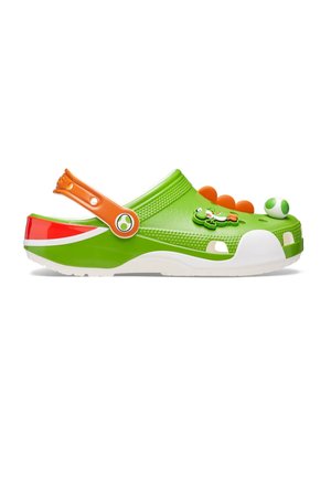 Sabot en caoutchouc vert avec bride de talon orange, personnage Yoshi et décorations d'œufs, semelle blanche et picots ressemblant à des dinosaures sur le dessus.