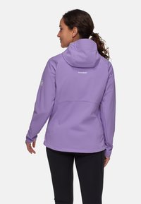 Giacca softshell viola con cappuccio, dotata di un design aderente, polsini elasticizzati e logo Mammut sulla schiena e sulla manica.