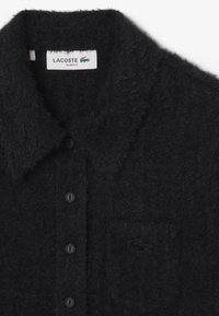 Camisa de lana negra fuzzy de botones con cuello, que presenta un corte slim, cinco botones negros y un logo bordado en tono. 
