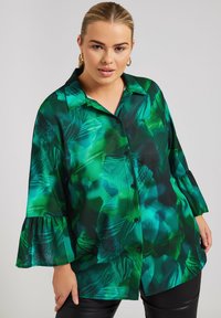 Camisa de estampado floral verde con botón frontal, puños enrollables y un corte relajado. Fabricada con un tejido ligero de textura suave.