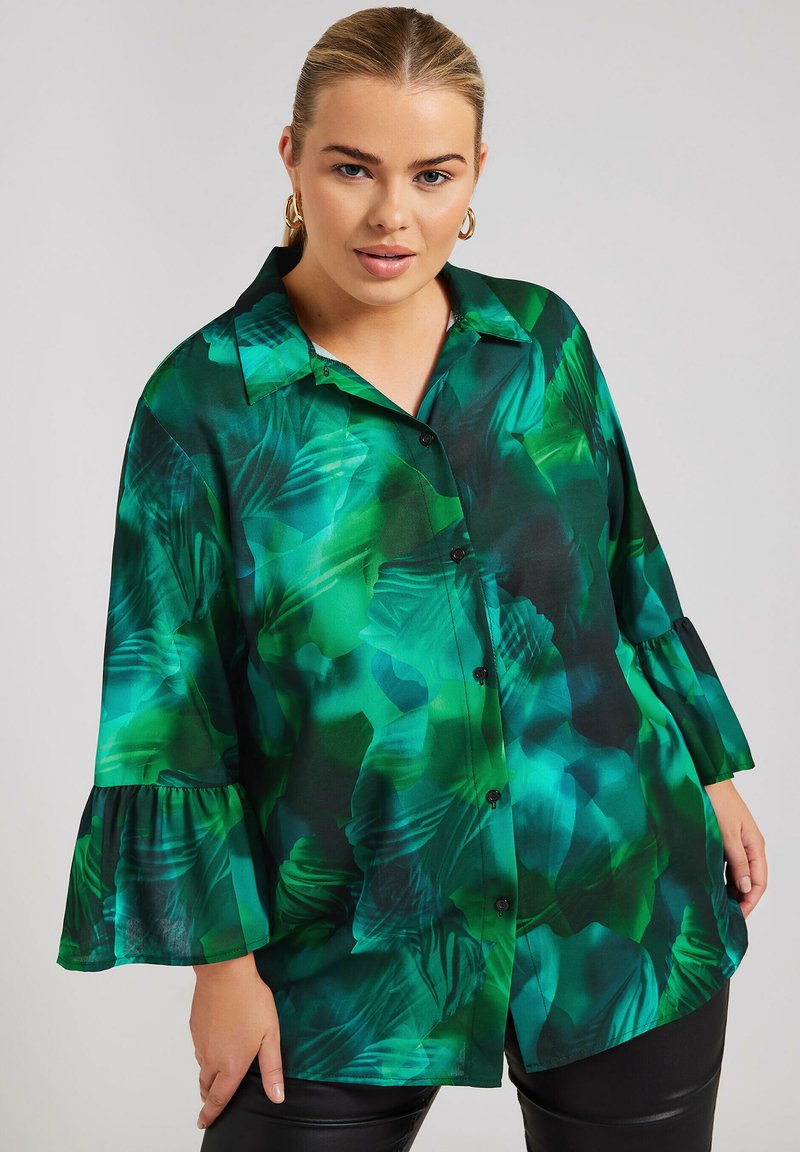 Camisa de estampado floral verde con botón frontal, puños enrollables y un corte relajado. Fabricada con un tejido ligero de textura suave.