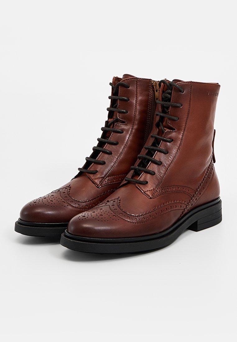 Braune Leder-Ankle-Boots mit Brogue-Design, ausgestattet mit einer Schnürung vorne und einem seitlichen Reißverschluss. Texturierte Details an der Zehenpartie und dem oberen Teil.