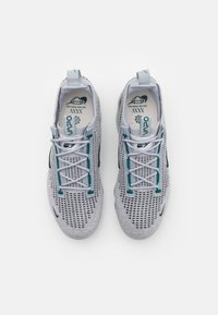 Ljust grå mesh-sneakers med teal-färger, rund tå och platta snören. Har en luftig ovandel med en texturerad design och vadderad krage.