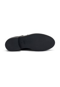 Suela de zapato negra con una superficie texturizada y un sutil branding. Forma curva, sin tacón visible y un contorno suave.