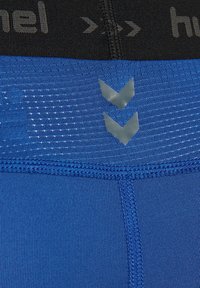 Niebieskie szorty sportowe z teksturowanej tkaniny, z czarnym elastycznym paskiem z logo oraz odblaskowymi akcentami w kształcie chevronu w okolicy pasa.
