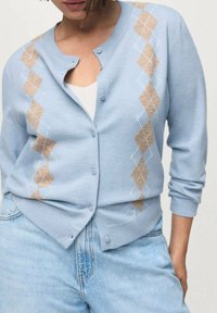Ljusblå cardigan i mjukt tyg, med en beige argyle-mönster och knappstängning, långa ärmar och avslappnad passform.