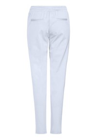 Ljusblå svettbyxor med en mjuk textur, med dragsko i midjan och två bakfickor. Benen smalnar av mot vristerna.