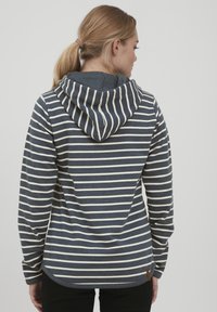 Sudadera de rayas en navy y crema, con capucha ajustable, mangas largas y un dobladillo redondeado. Fabricada en un tejido suave y texturizado.