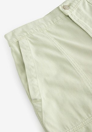 Gaiši zaļi plandoši šorti, izgatavoti no teksturēta auduma. Raksturīga pogu aizdare un redzamas dūriena detaļas gar jostasvietu un šuvēm.