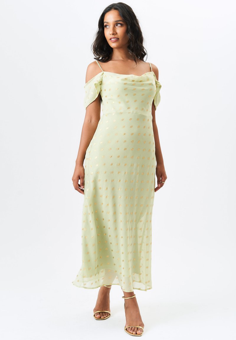 Light green midi dress with off-shoulder sleeves, featuring gold dot patterns. Made from a sheer material with a flowy silhouette and slits.