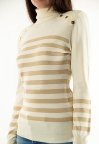 Maglione a collo alto lavorato a maglia color crema con strisce beige alternate opache e lucide, caratterizzato da dettagli in metallo dorato sulle spalle.