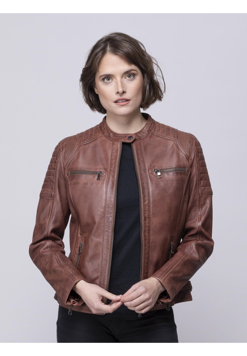Brown leather jacket with a slim fit, featuring zippered pockets, a round collar, and quilted shoulder detail. Smooth texture throughout.