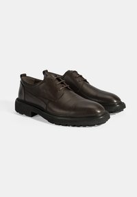 Chaussures en cuir marron avec une finition lisse, à lacets, bout rond et semelle en caoutchouc noir texturé pour une meilleure adhérence.