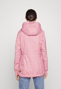 Rosa mönstrad jacka med huva, med en insvängd midja, elastiska muddar och en dekorativ logopatch på den nedre sidan.