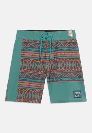 Blågrønne boardshorts med orange og mørkegrå geometriske stamme-mønstre, blågrøn snor og et lille rektangulært logo-mærke ved kanten.