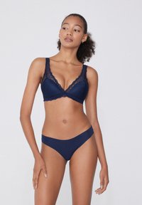 Námořnický modrý krajkový podprsenka se širokými ramínky a hlubokým výstřihem, spárovaná s odpovídajícími bikinovými kalhotkami s nízkým pasem a měkkou texturou.