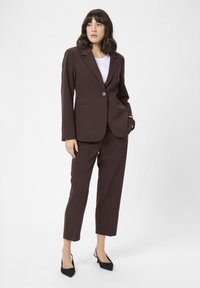 Bordeaux blazer met een enkele knoopsluiting, gecombineerd met bijpassende op maat gemaakte broek. Bevat een slank ontwerp, een zachte textuur en geen zichtbare patronen.