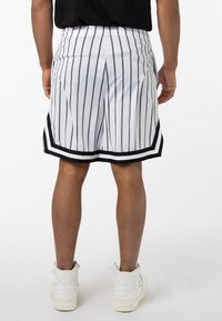 White shorts with black vertical stripes, featuring a solid black hem and side accents. Made from breathable material.