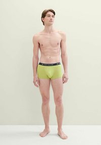 Zöld boxeralsó fekete derékkal, amelyen a "TOM TAILOR" logó látható. Az anyag simának és testhez állónak tűnik.