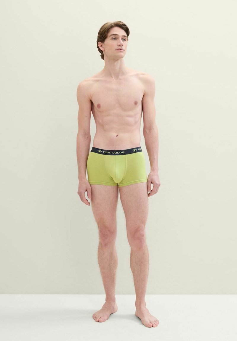 Zelené boxerky s čiernym pásom, na ktorom je logo "TOM TAILOR". Tkanina vyzerá hladko a tesne prilieha k telu.