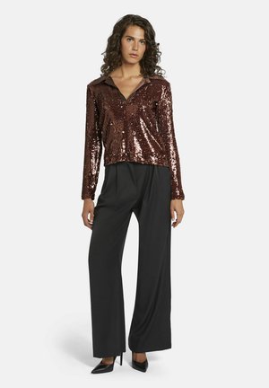 Haut long à manches en sequins bronze avec un col, associé à un pantalon noir à jambes larges et des talons aiguilles noirs, offrant une apparence brillante et texturée.