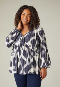 Blusa a maniche lunghe navy e bianca con motivo, scollo a V e dettaglio con coulisse in vita; il tessuto ha un aspetto morbido e strutturato.