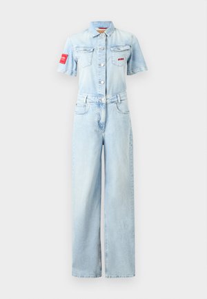 Φωτεινό γαλάζιο τζιν ολόσωμο με κοντά μανίκια, εμπρός με κουμπιά, γιακά, τσέπες στο στήθος, κόκκινο μπάλωμα στο μανίκι και παντελόνι με φαρδιά μπατζάκια.