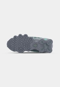Suela de zapato con una base de goma gris; presenta patrones de agarre texturizados y un diseño redondeado. Incluye acentos en color verde menta y detalles de logotipo.