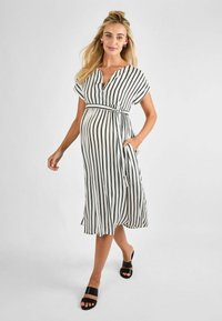 Vestito midi a righe in bianco e nero, con scollatura a V, maniche corte, una cintura da annodare in vita e tasche. Tessuto morbido che cade delicatamente.