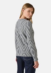 Maglione grigio con motivo geometrico bianco, realizzato in materiale morbido e testurizzato. Caratterizzato da una vestibilità comoda e maniche lunghe.