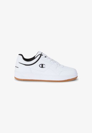 Zapatilla baja blanca con ribetes y logotipo negros, cordones blancos y suela de goma, vista lateral sobre fondo blanco.