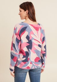 Pull en tricot rose, bleu et marron avec des motifs de feuilles. Comprend des manches longues, une coupe décontractée et un col rond.